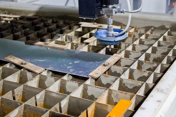 First, the sheet metal is placed on the cutting surface while the jet is calibrated and aligned