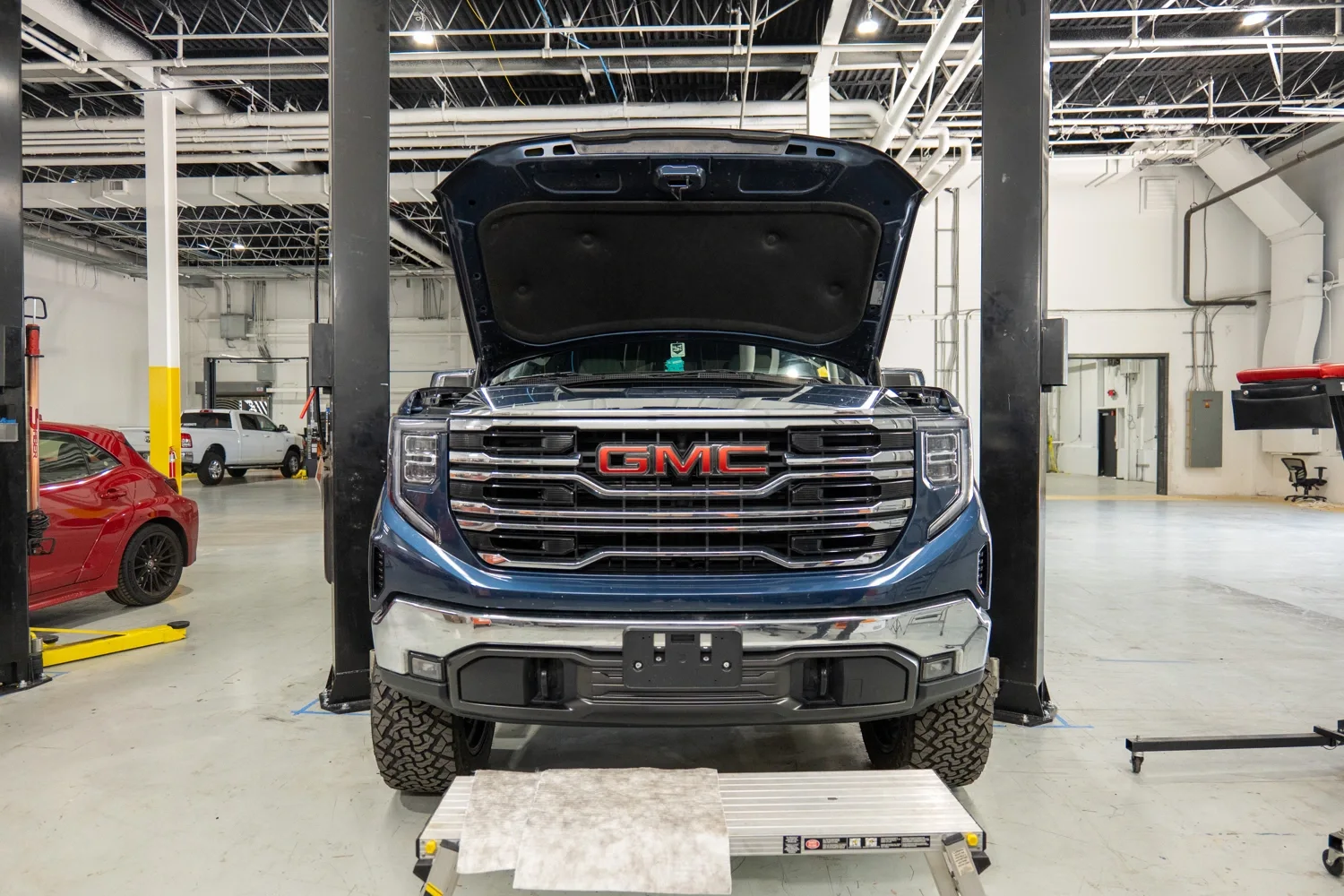 An image of a GMC Sierra 1500 with its hood open in a garage.