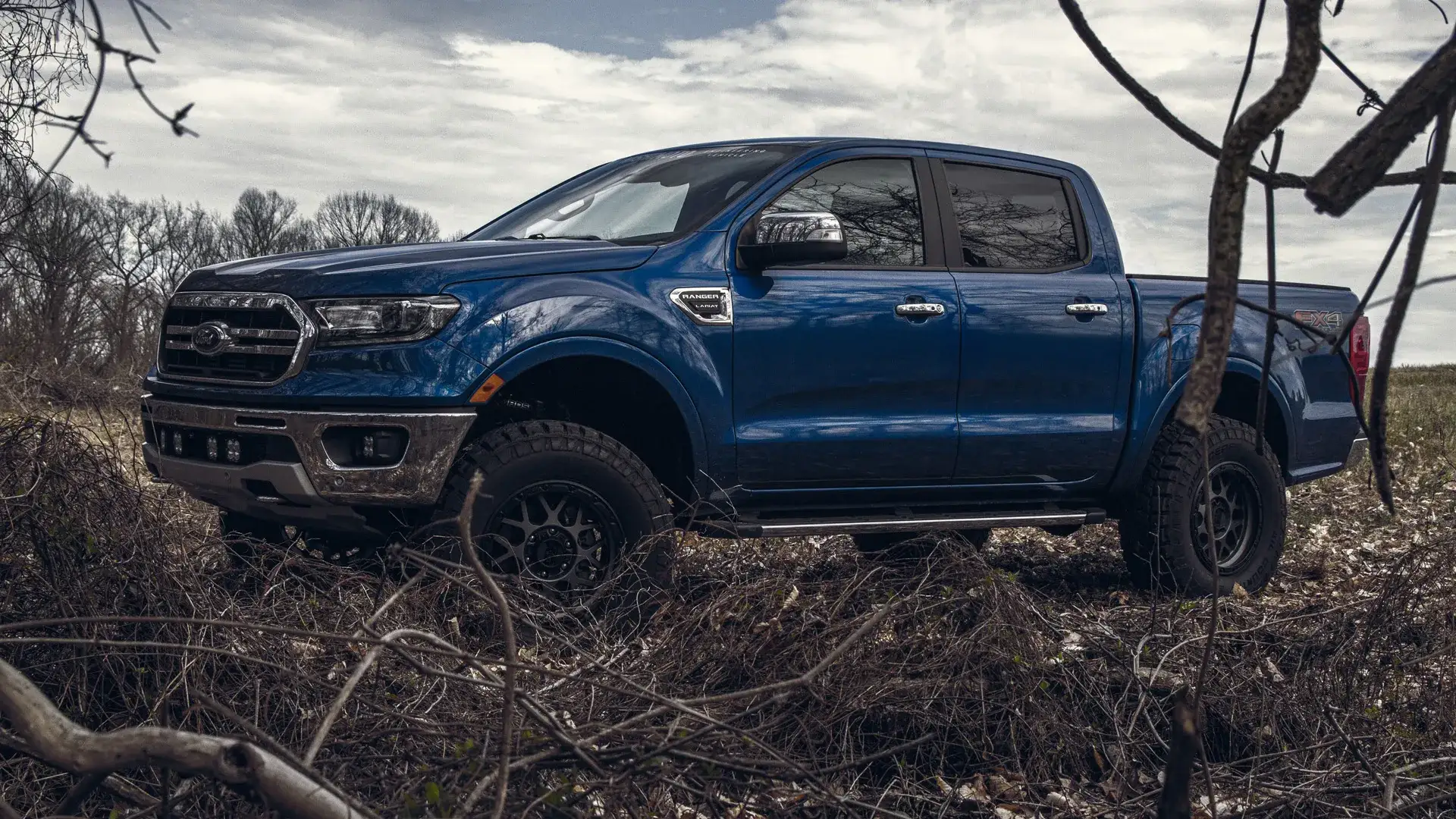 Blue Ford pickup truck with lift kit and off-road tires.