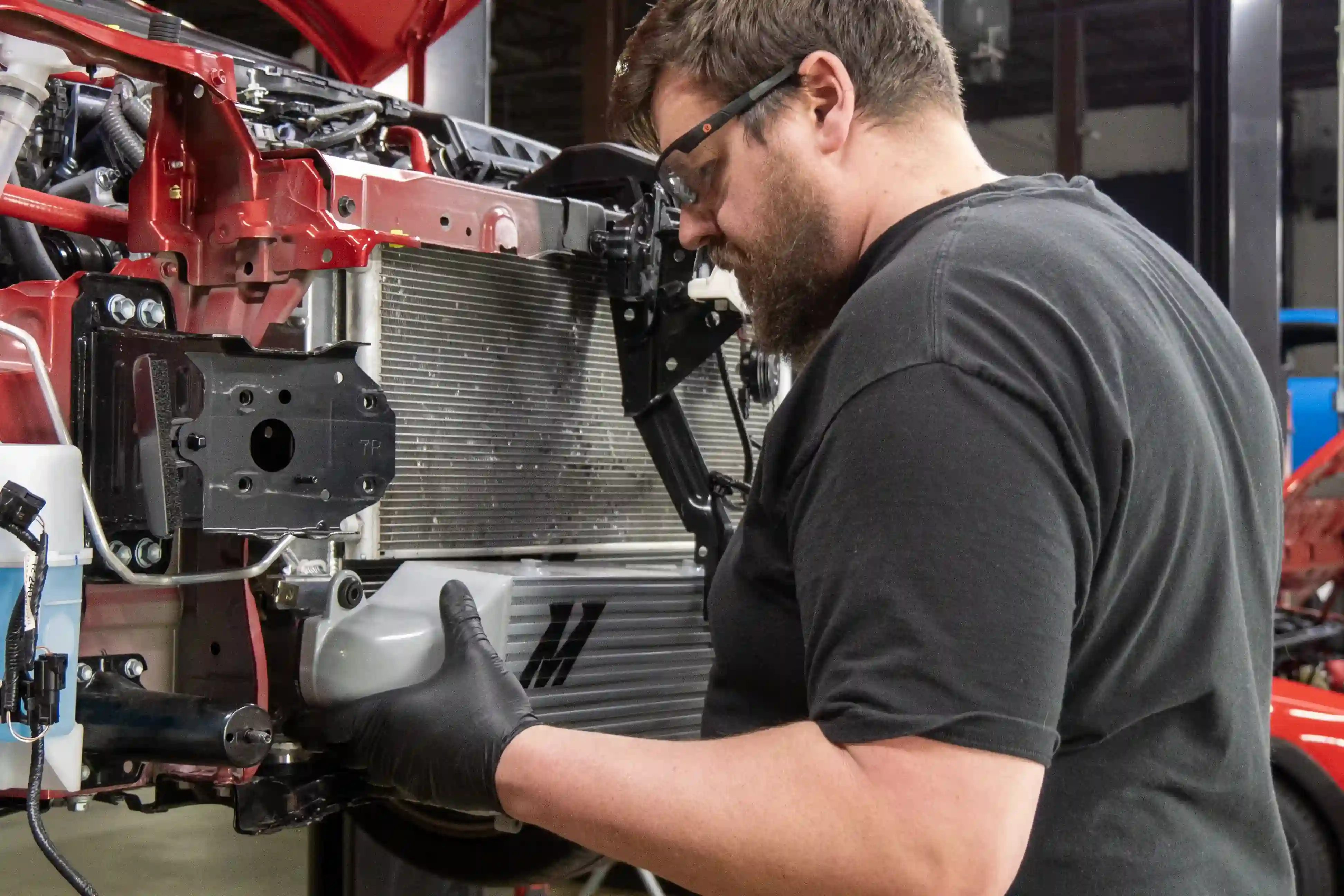 An image of our engineer installing the Mishimoto intercooler to a red 2023 Toyota GR Corolla.