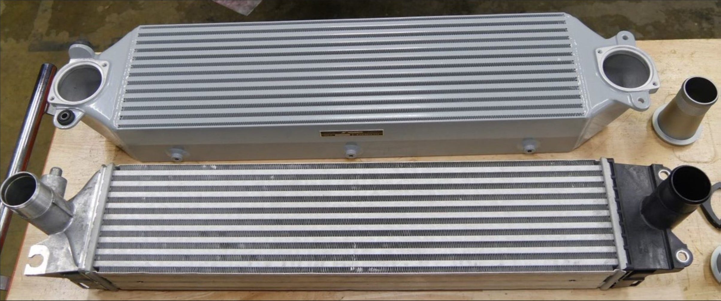 An image showing a side-by-side comparison of the Mishimoto performance intercooler (top) and the stock Toyota intercooler (bottom).